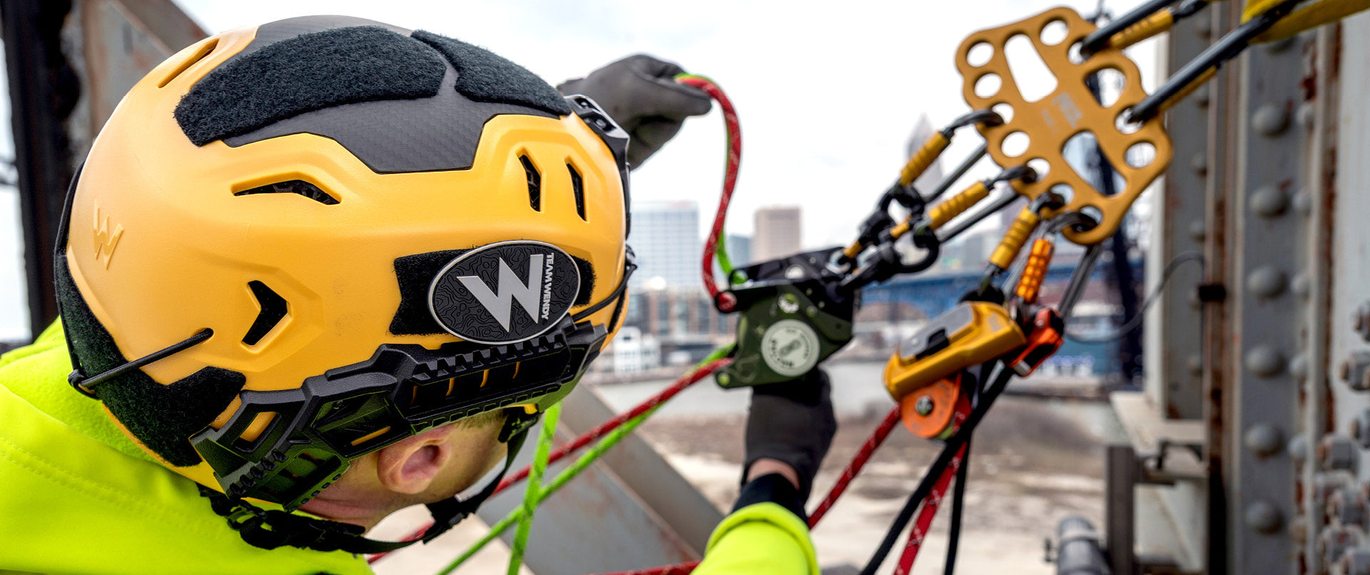 A search and rescue operator wearing a yellow Team Wendy RECON Tactical helmet and preparing to rappel. 
